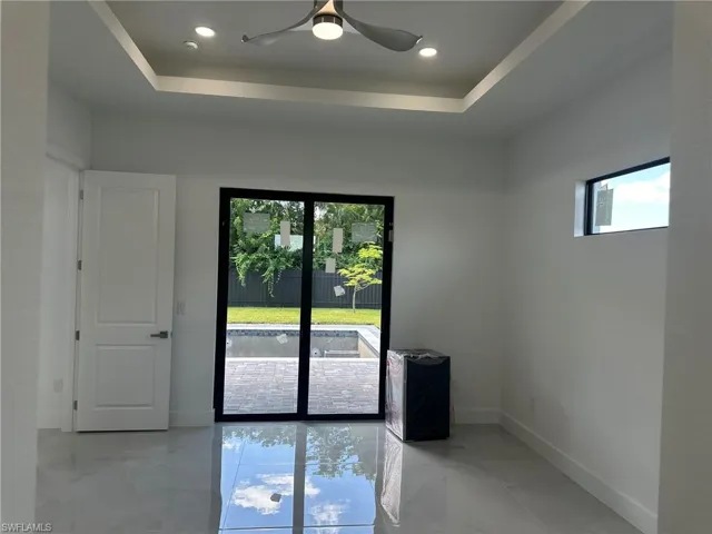 Empty room featuring light tile patterned flooring, a raised ceiling, and ceiling fan