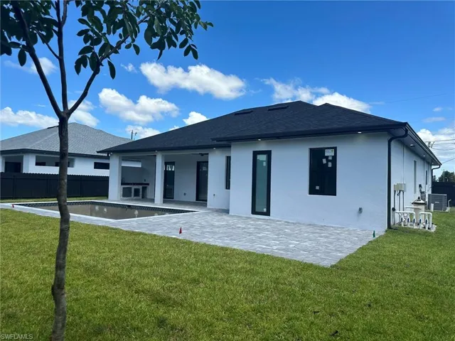 Rear view of property featuring a patio, central air condition unit, and a lawn