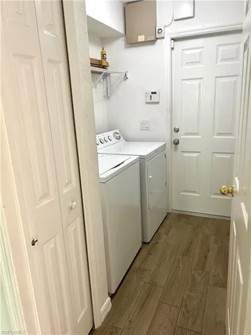 Laundry room with wood finish floors and washer and clothes dryer