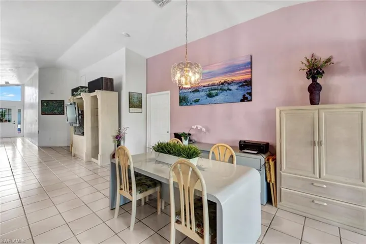 Dining room with a chandelier, lofted ceiling, and light tile flooring