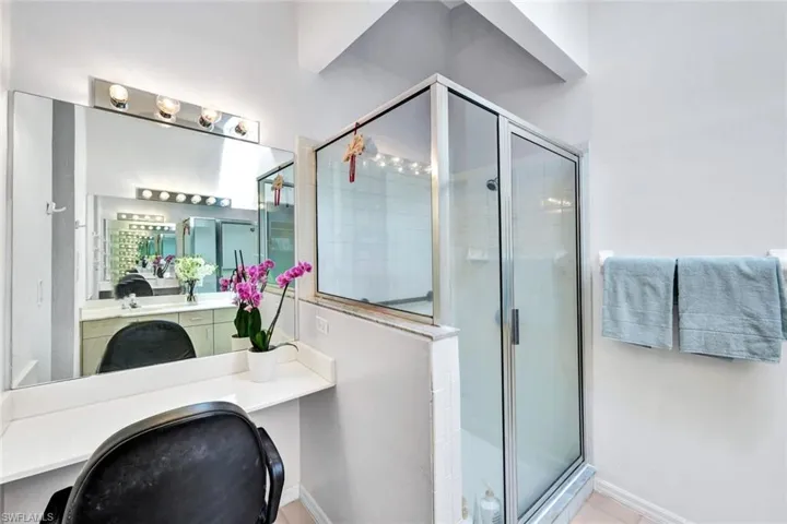 Bathroom featuring a shower with door, tile flooring, and vanity