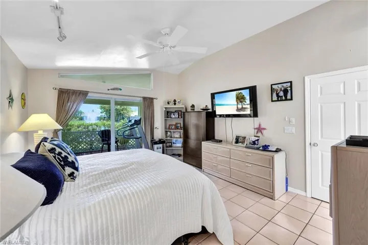 Tiled bedroom with ceiling fan, lofted ceiling, access to outside, and rail lighting