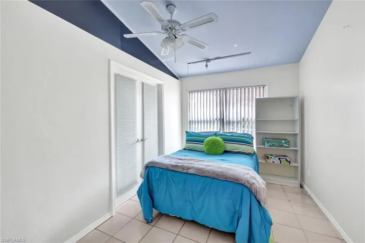 Tiled bedroom with ceiling fan, vaulted ceiling, and rail lighting. This room is decorated as a bedroom but is the Den open to the living room