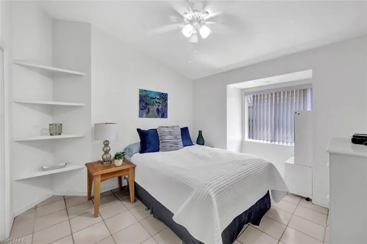 Bedroom with ceiling fan, light tile flooring, and lofted ceiling. First Guest Bedroom