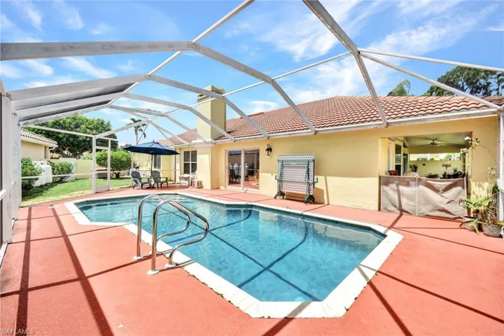 View of pool with glass enclosure and a patio area