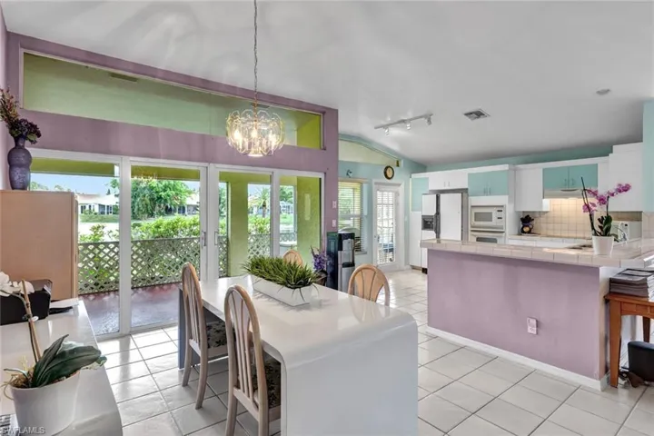 Dining room with a notable chandelier, light tile floors, rail lighting, and vaulted ceiling