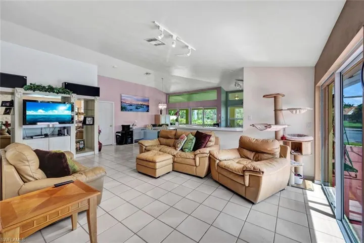 Tiled living room featuring vaulted ceiling and rail lighting. The door in the picture is the door to the master bedroom.