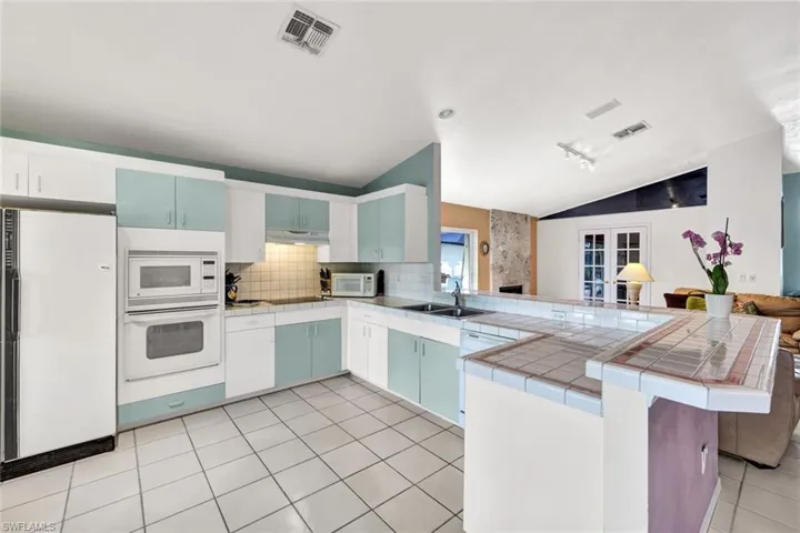 Kitchen featuring kitchen peninsula, tasteful backsplash, white appliances, sink, and lofted ceiling