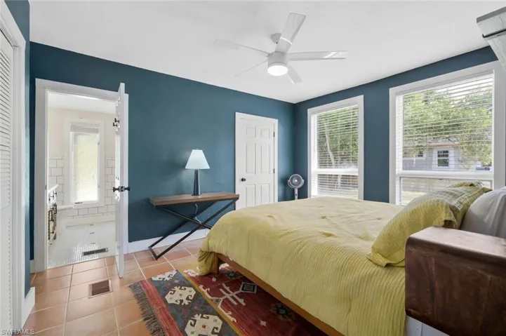 Bedroom with light tile patterned floors, multiple windows, and ceiling fan