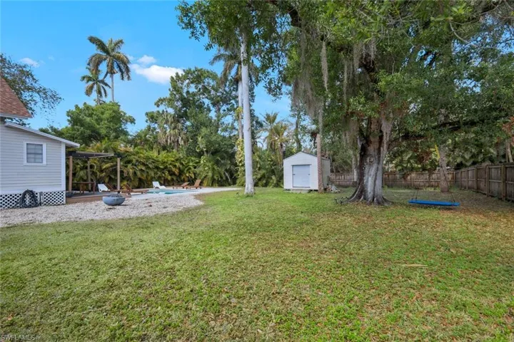 Fenced backyard with a storage unit, an outdoor pool, and a patio area