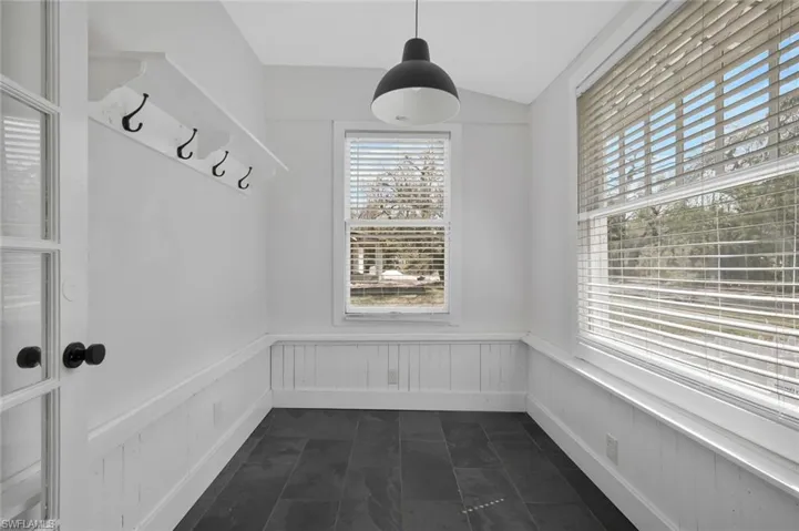 Mudroom featuring dark tile patterned floors, wainscoting, and lofted ceiling
