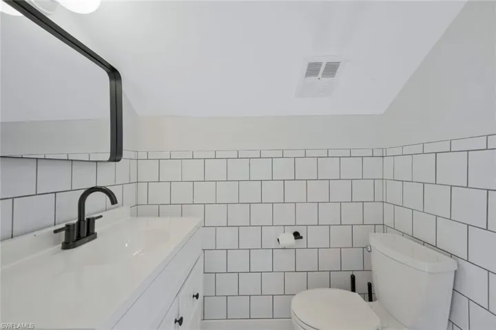 Half bath featuring vanity and tile walls