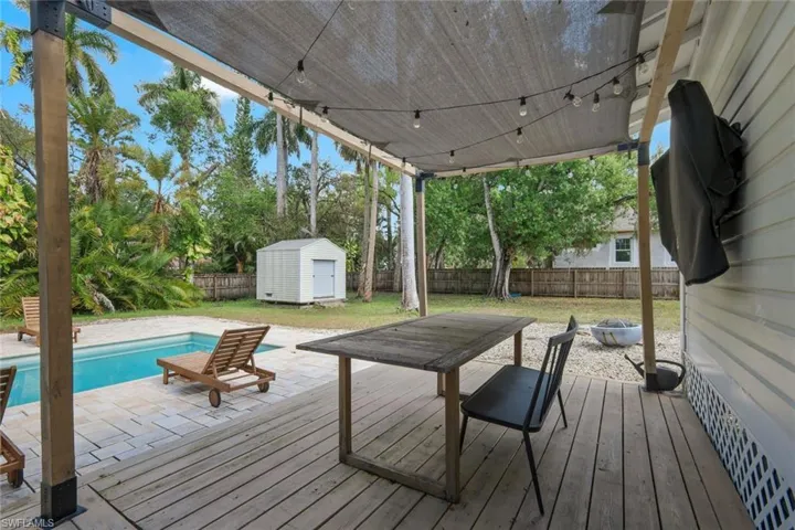 Deck featuring a patio, a fenced backyard, a fire pit, a storage unit, and outdoor dining area