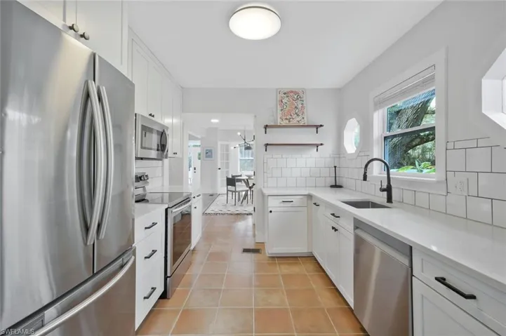 Kitchen with stainless steel appliances, white cabinetry, and light stone countertops