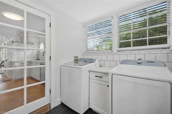 Laundry area with independent washer and dryer, plenty of natural light, and dark tile patterned flooring