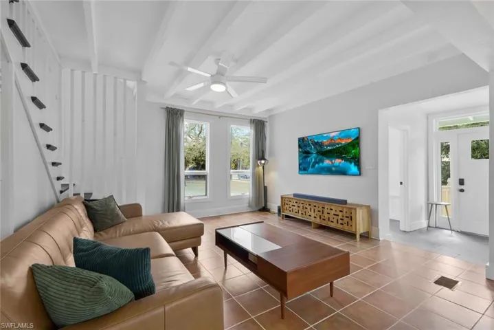 Living area featuring ceiling fan, beamed ceiling, and light tile patterned floors