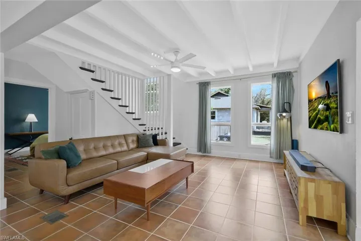 Living area featuring beam ceiling, ceiling fan, and light tile patterned floors