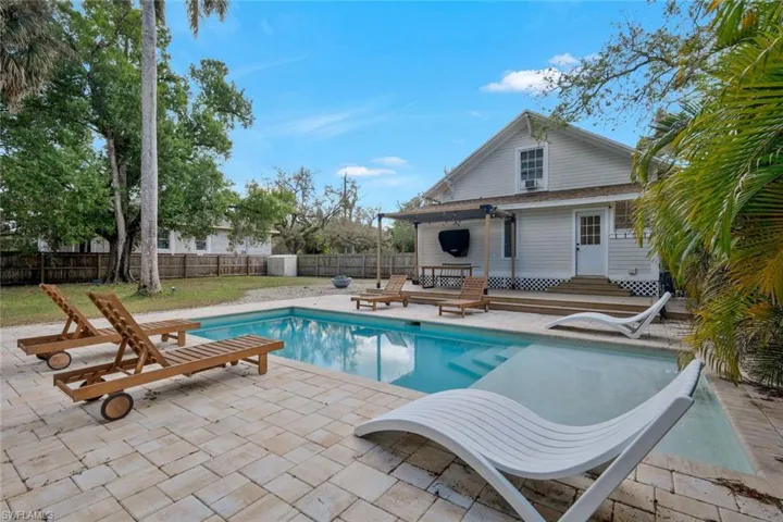 View of swimming pool featuring patio surround, a fenced backyard, a wooden deck, and entry steps