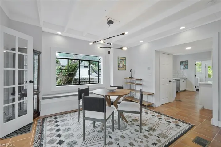 Dining area with light tile patterned floors, a chandelier, and beamed ceiling