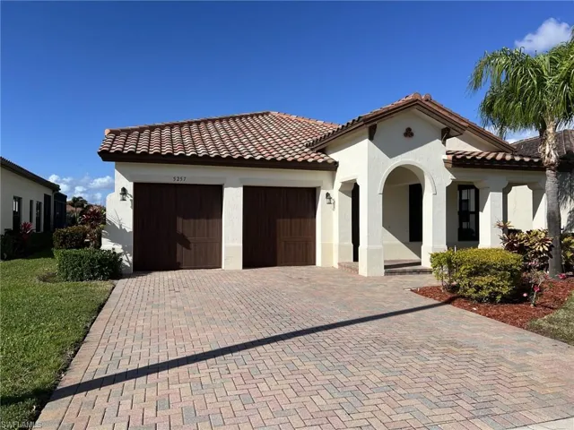 Mediterranean / spanish-style house with a tile roof, stucco siding, decorative driveway, and a garage