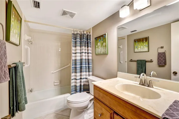 Full bath featuring shower / bath combo with shower curtain, vanity, and light tile patterned floors