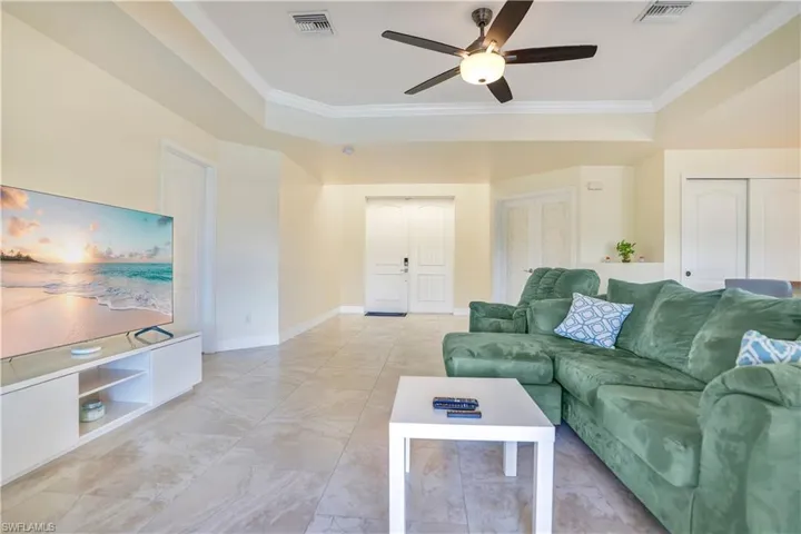 Living room featuring crown molding, ceiling fan, and a raised ceiling