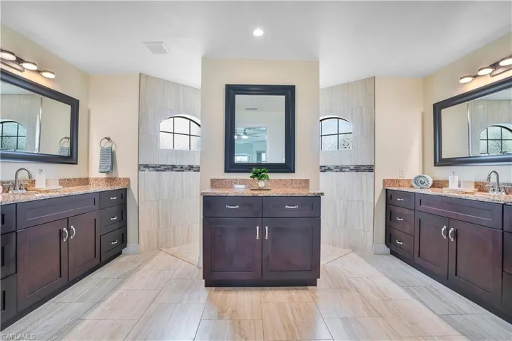 Full bathroom featuring two vanities, walk in shower, and recessed lighting
