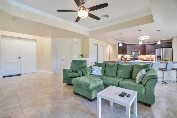 Living area with ornamental molding, ceiling fan, and a raised ceiling