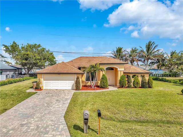View of front of home with a garage, a front yard, decorative driveway, and stucco siding