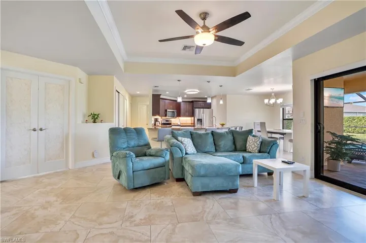 Living area featuring french doors, ceiling fan, crown molding, a chandelier, and a raised ceiling