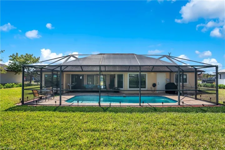 Back of house with a lawn, an outdoor pool, a sunroom, and a lanai