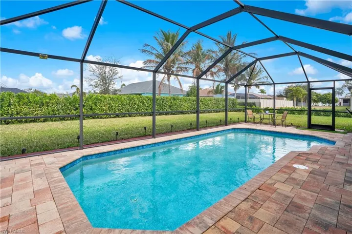 Outdoor pool featuring glass enclosure, a sunroom, and a patio area