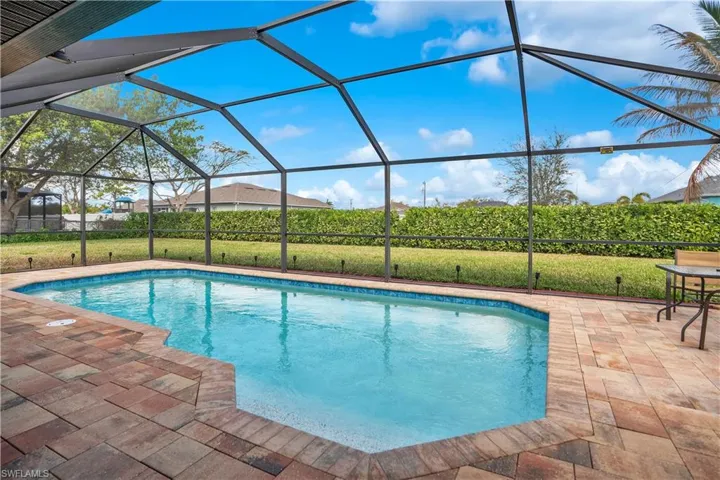 Outdoor pool with a lawn, a sunroom, a patio area, and a lanai
