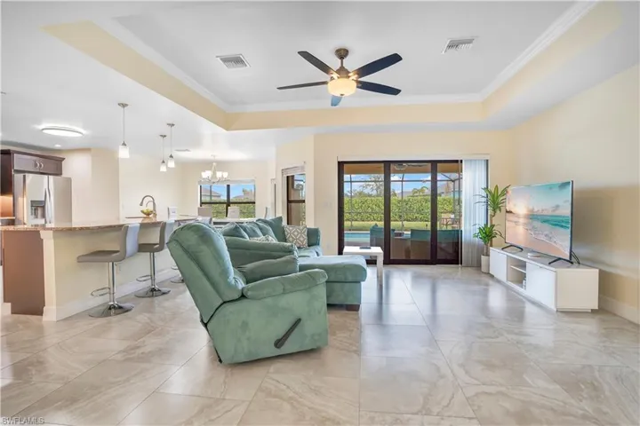 Living room featuring crown molding, a raised ceiling, hanging lights, and ceiling fan