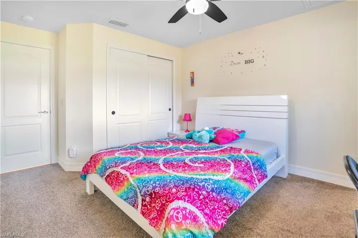 Bedroom featuring a closet, light colored carpet, and a ceiling fan
