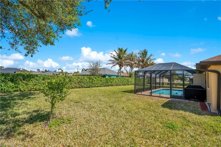 View of grassy yard with a sunroom, glass enclosure, and a patio