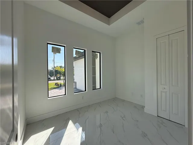 Unfurnished room with marble finish floor, visible vents, baseboards, and a raised ceiling