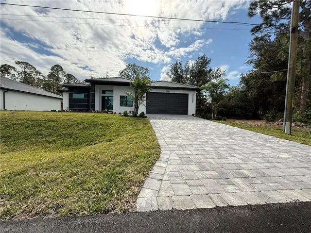 Prairie-style house featuring a front yard, an attached garage, decorative driveway, and stucco siding