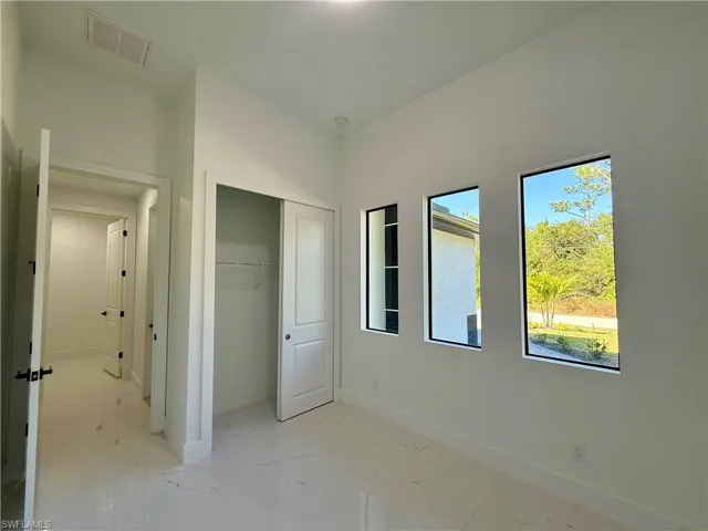 Unfurnished bedroom with a closet and light marble finish floors