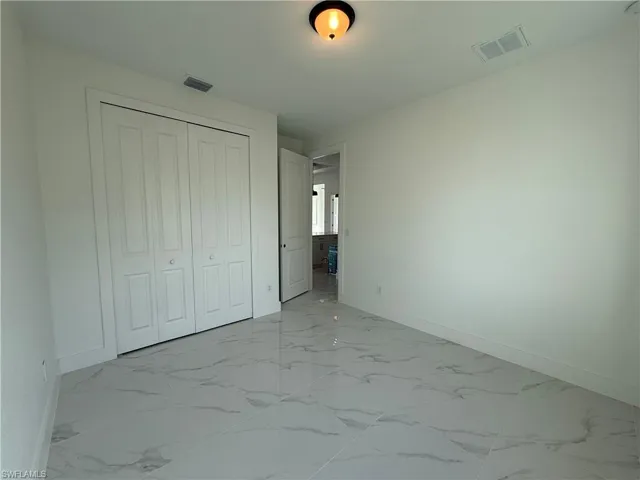 Unfurnished bedroom featuring visible vents, marble finish floor, and a closet