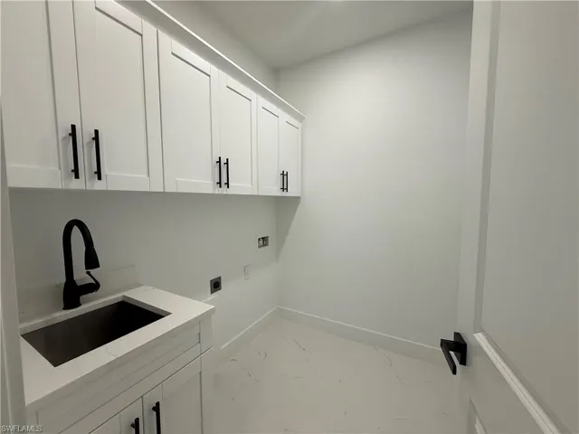 Laundry room with cabinet space, hookup for a washing machine, light marble finish floors, and hookup for an electric dryer
