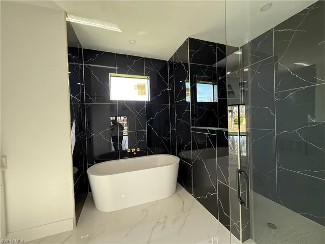 Full bath with a walk in shower, a freestanding tub, and marble finish floor