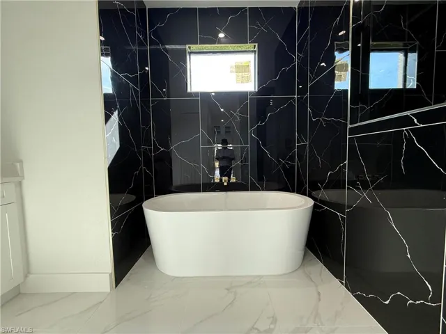 Bathroom featuring a soaking tub and marble finish floor