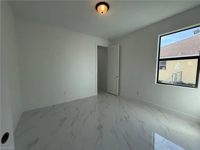 Spare room featuring marble finish floor and baseboards