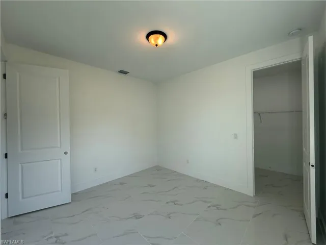 Unfurnished bedroom featuring a closet, visible vents, marble finish floor, and baseboards