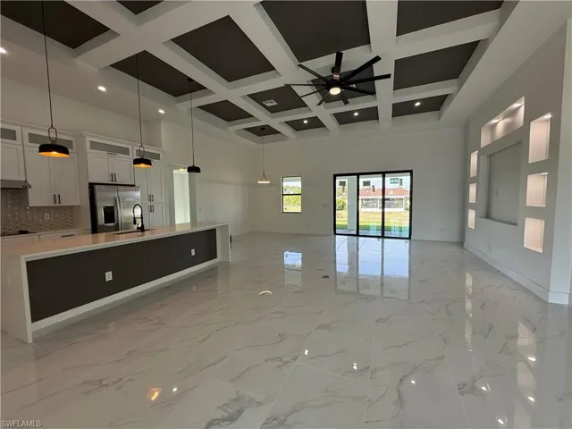 Unfurnished living room with beamed ceiling, a ceiling fan, a high ceiling, marble finish floor, and coffered ceiling