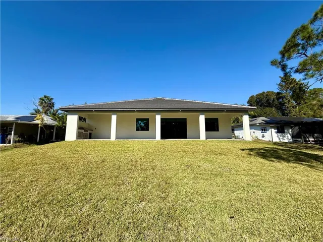 Rear view of property featuring a yard, stucco siding, and a patio area