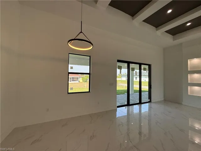 Spare room featuring marble finish floor, baseboards, plenty of natural light, and a towering ceiling
