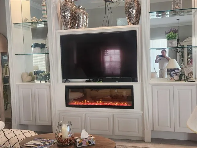Detailed view of crown molding, built in features, and a glass covered fireplace