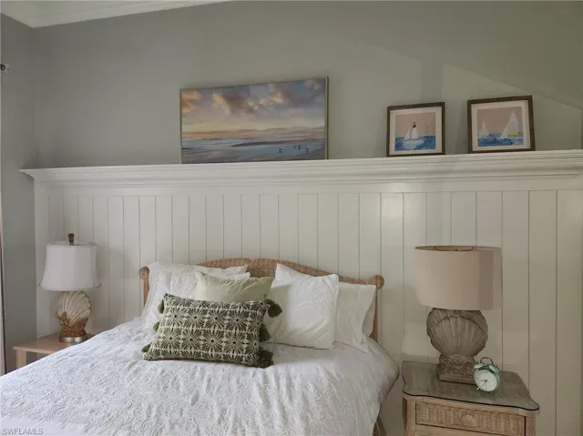 Bedroom with crown molding, wainscoting, and lofted ceiling